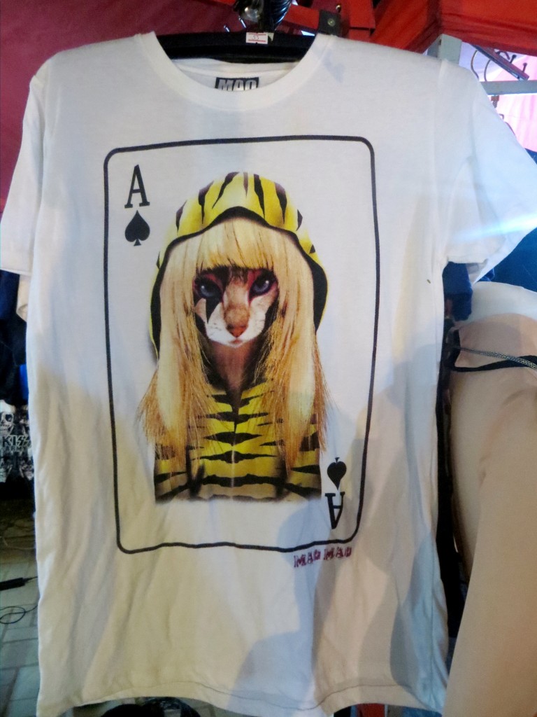 Blah blah blah - this is a picture of a cat w/ face paint wearing a blonde wig & a tiger striped hoodie, as an Ace of Spades, on a t-shirt.